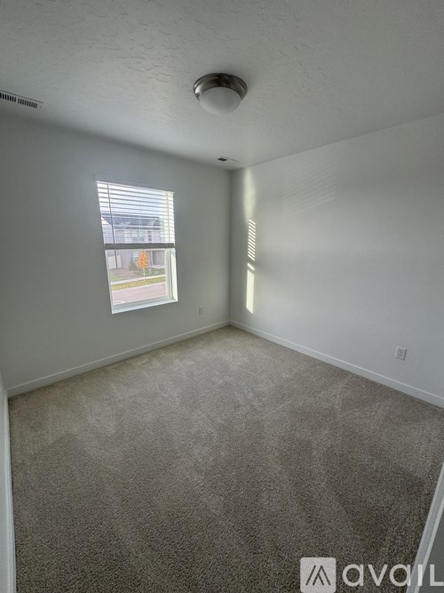 A room with a carpeted floor and a window letting in light.