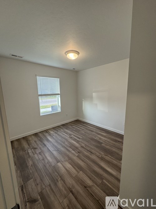 A room with wooden flooring and a window with blinds.