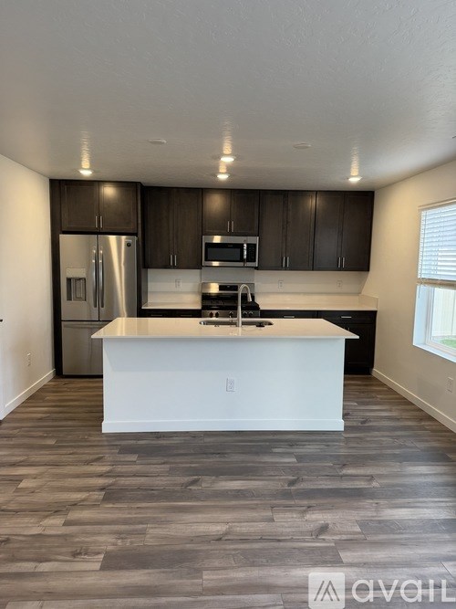 A kitchen with a white island in the middle of a room with wood flooring.