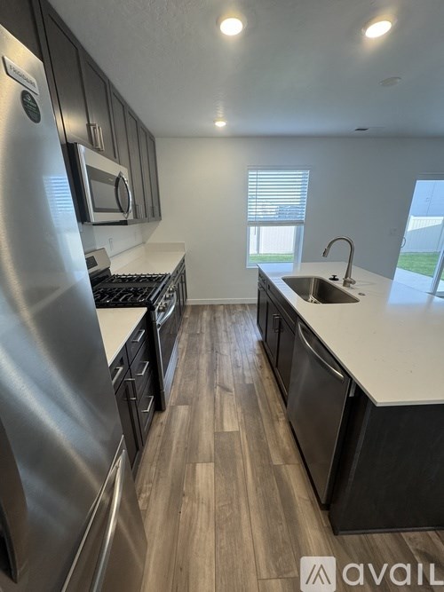 A kitchen with a stainless steel refrigerator and wooden flooring.