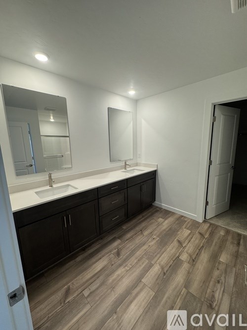 A bathroom with a sink, mirror, and wooden floors.