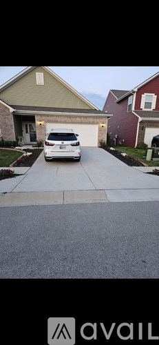 A white car is parked in front of a house.