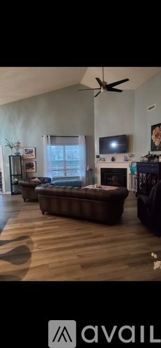 A living room with a brown sofa and a television on the wall.