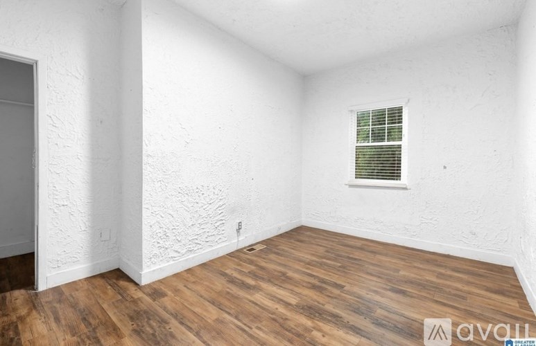 A room with wooden floors and a window with blinds.