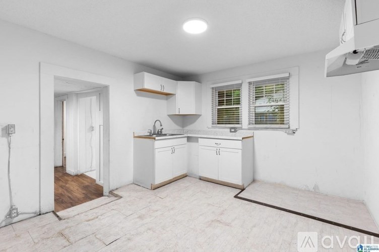A kitchen with white cabinets and a wooden floor.