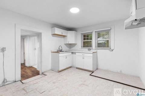 A kitchen with white cabinets and a wooden floor.