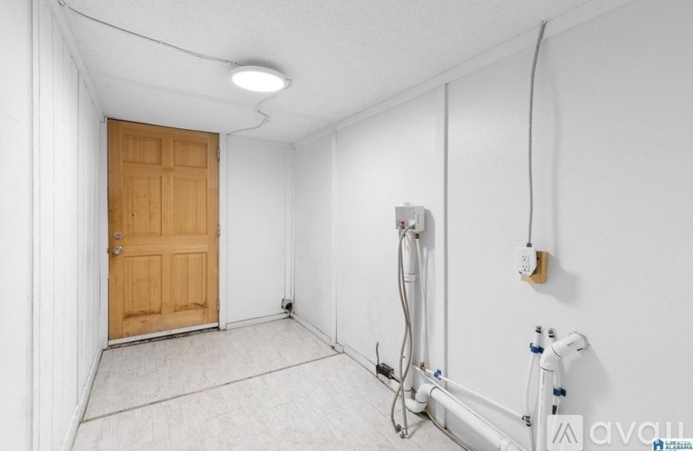 A room with a wooden door and a white wall with a cable running along it.