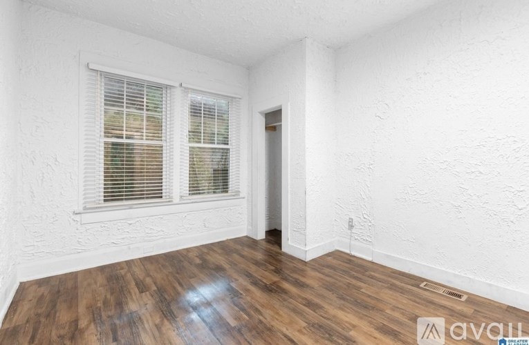 A room with wooden flooring and a window with blinds.