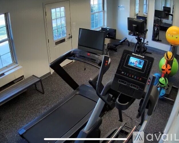 A treadmill with a screen and a bench in a room.