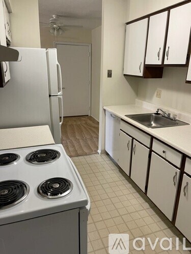 A kitchen with a white fridge, white stove, and white cabinets.