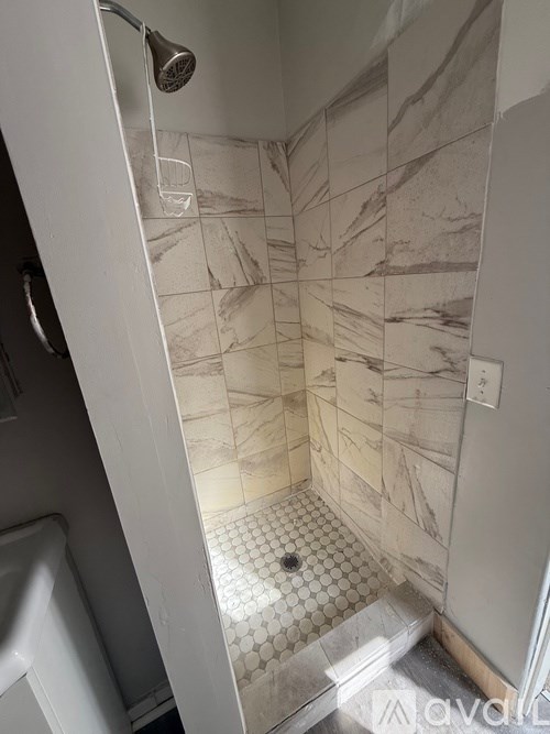 A shower with a glass of water underneath it.