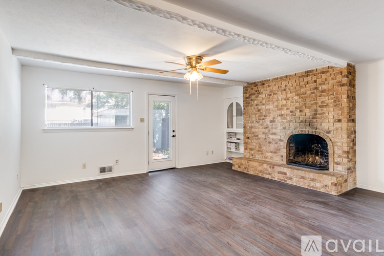 A room with a brick fireplace and wooden floors.