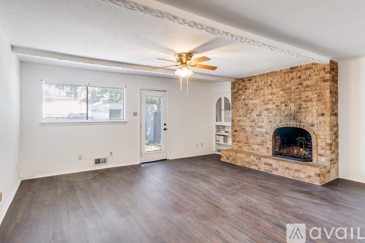 A room with a brick fireplace and wooden floors.
