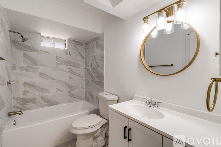 A bathroom with a marble tile wall and a round mirror.