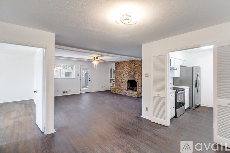 A spacious living room with a fireplace and a kitchen area in the background.