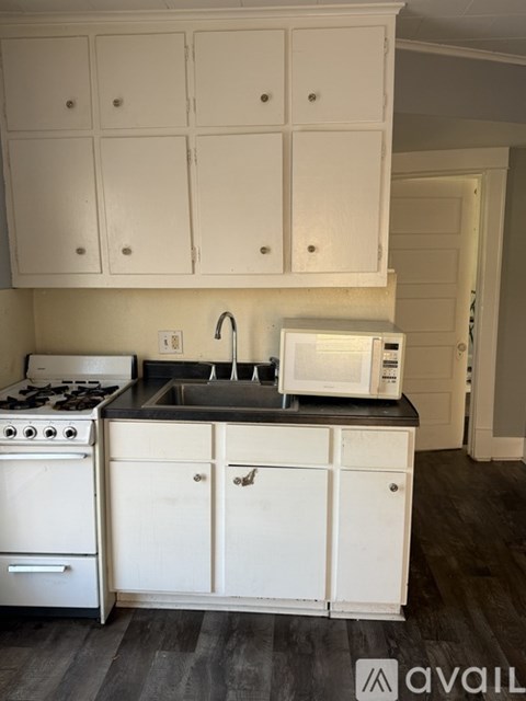 A kitchen with white cabinets and a black countertop.