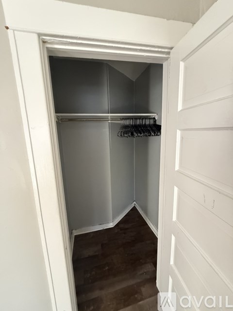 A white closet with a shelf and clothes hanging on it.
