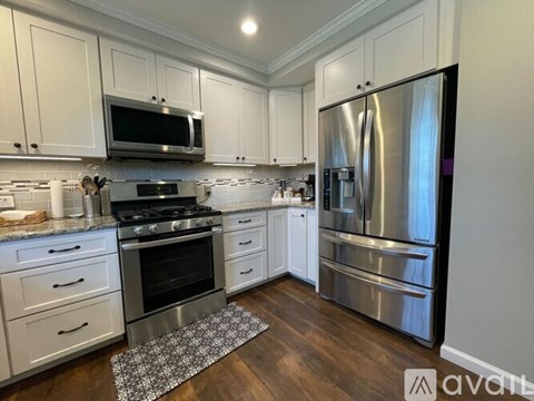 A kitchen with white cabinets and a stainless steel refrigerator.