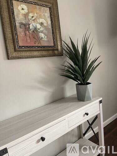 A potted plant sits on a desk next to a framed picture of flowers.