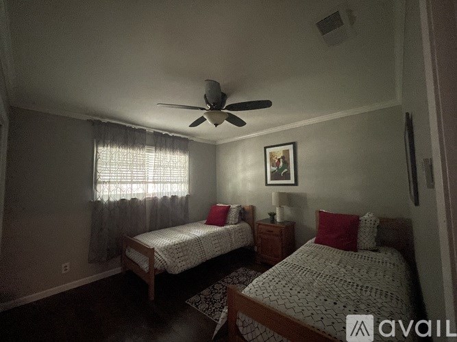 A bedroom with two beds and a ceiling fan.