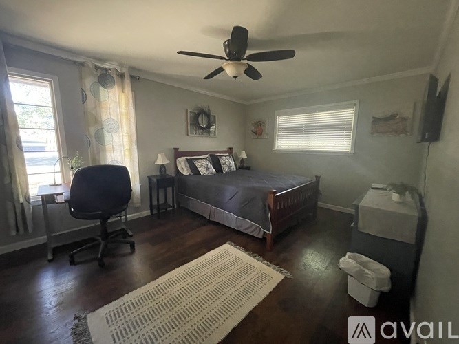 A bedroom with a bed, chair, and ceiling fan.