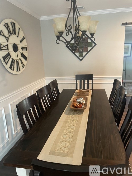 A long wooden table with a clock on the wall above it.