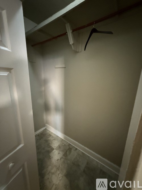 A white door is on the left side of a room with a coat hanger on the wall.