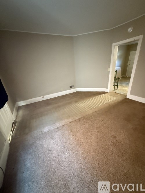 A room with a carpeted floor and a doorway leading to another room.