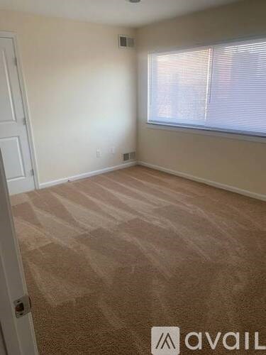 A room with a carpeted floor and a window with blinds.
