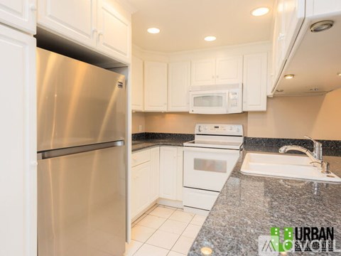 A kitchen with a stainless steel refrigerator and white cabinets.
