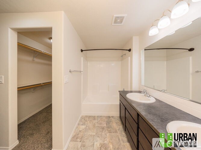 A bathroom with a walk-in shower and double sinks.