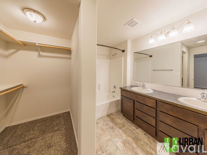 A bathroom with a vanity, mirror, and a towel bar.