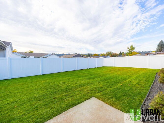 A white fence with a green lawn in front of it.