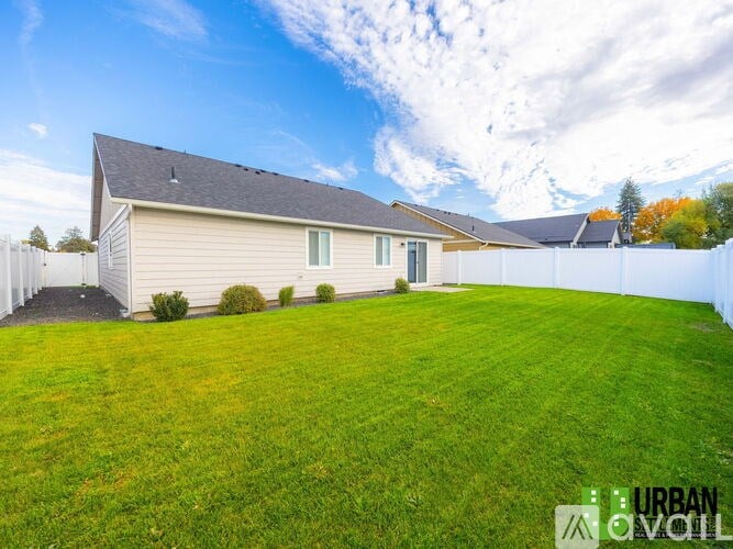 A house with a white fence and a green lawn in front.