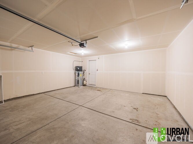 A large, empty room with a concrete floor and walls, and a door in the center.