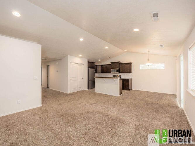 A spacious living room with a kitchenette in the background.