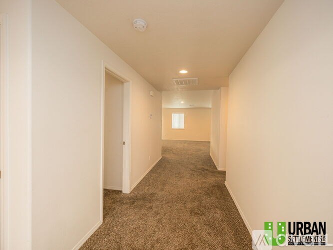 A long hallway with carpeted flooring and white walls.