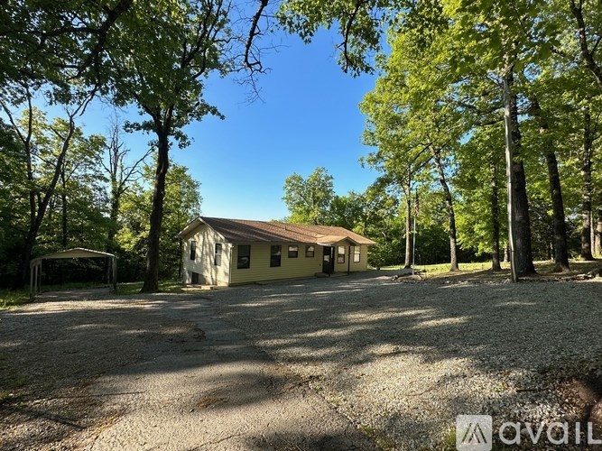 A small house is surrounded by trees in a wooded area.