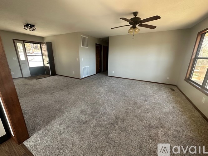 A spacious room with a ceiling fan and carpeted floor.