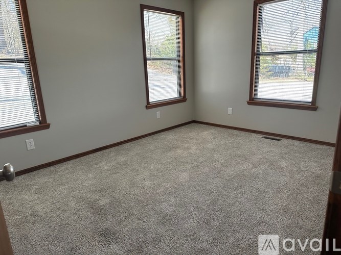 A room with two windows and carpeted floor.