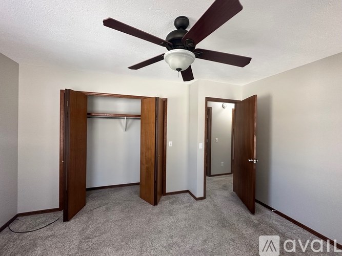 A room with a ceiling fan and two open doors.