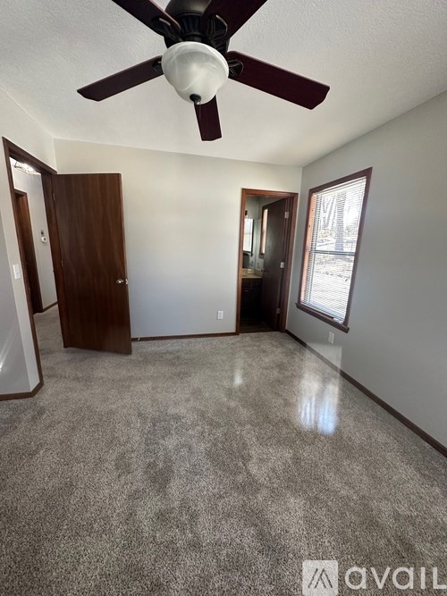 A room with a ceiling fan and carpeted floor.