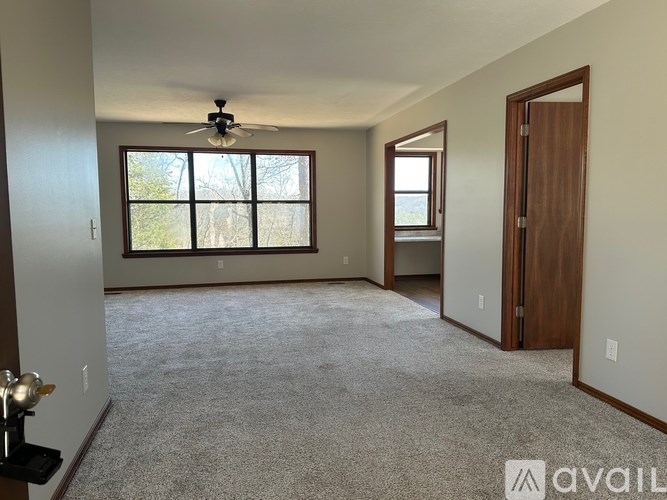 A spacious room with a ceiling fan and large windows.