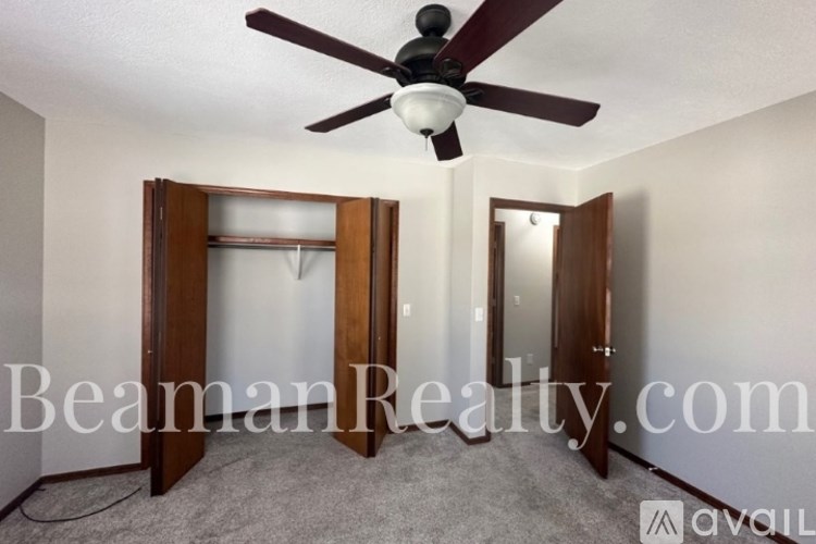 A room with a ceiling fan and a mirrored door.