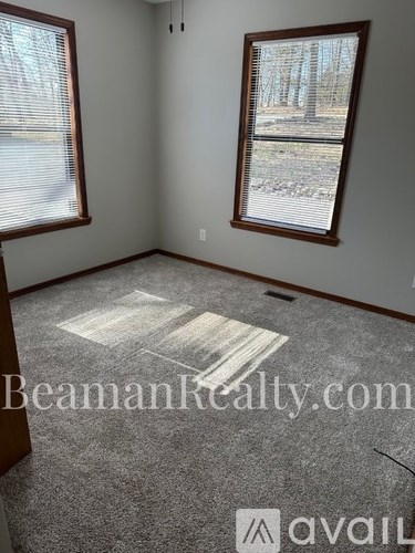 A room with a carpeted floor and two windows.