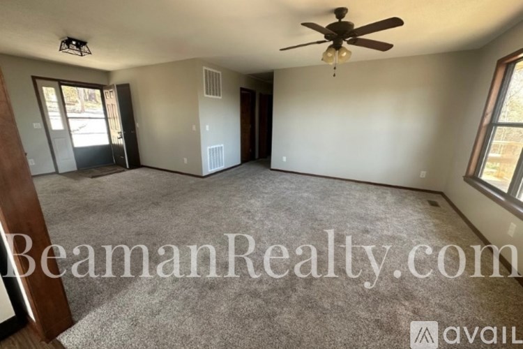 A spacious room with a ceiling fan and a carpeted floor.