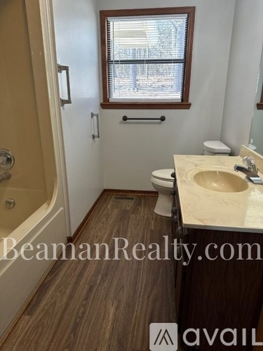 A bathroom with a toilet, sink, and a window.