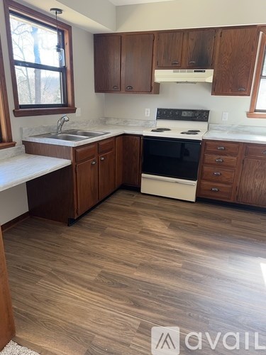A kitchen with wooden cabinets and a white stove top oven.