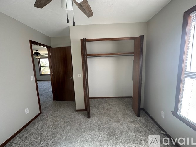 A room with a ceiling fan and a door leading to another room.