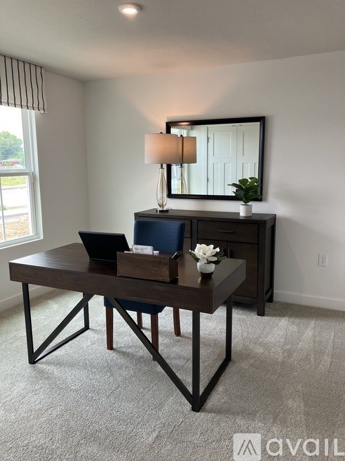 A table with a laptop and a flower vase on it.